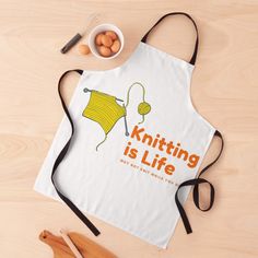 an apron that says knitting is life next to some eggs and utensils on a table