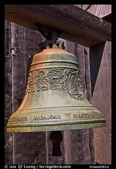 an old bell hanging from the side of a wooden building