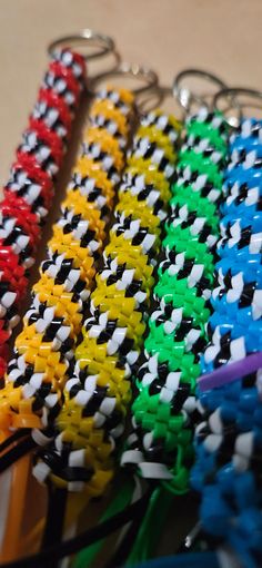 several different colors of key chains are on the table next to each other and one is black, white, yellow, red, green, blue