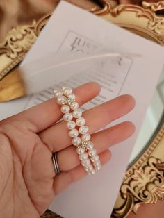 a woman's hand holding a pearl and diamond bracelet