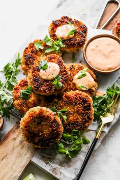 crab cakes on a plate with dipping sauce and garnishes next to it