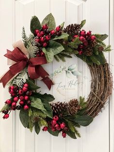 a wreath with red berries, pine cones and greenery is hung on the front door