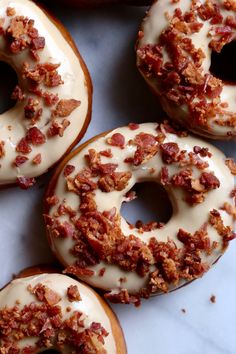 four donuts with white frosting and bacon on them