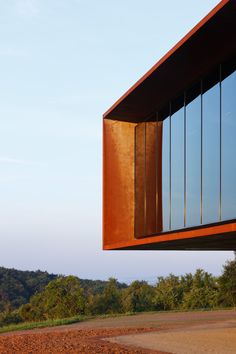 the side of a building with large windows on it's sides and trees in the background