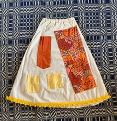 an orange and white skirt with yellow trims on it sitting on top of a blue rug