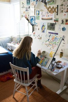 a woman sitting at a desk in front of a white board with pictures on it