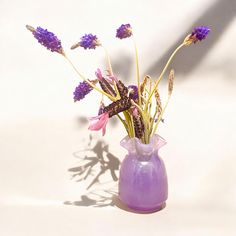 a purple vase filled with flowers on top of a table