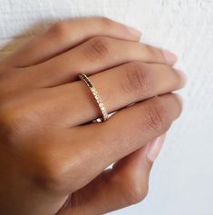 a woman's hand with a diamond ring on her left hand and the other hand holding it