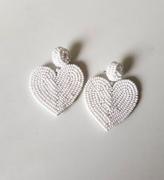 "Handmade white beaded Heart shape embroidered Earring Purely handmade seed beads embroidered heart earring looks so great. An ideal gift for bridesmaids. Earrings measure about approx. 2.10\" long and 2.10\" wide. PS: Carnation jewelry is handmade & handcrafted in India hence there is a possibility of a slight or small imperfection due to the fact that these are made by hand. I still make sure that every piece made here is perfect to look at. For more details, please see our shop policies f White Dangle Heart Bead Earrings, White Heart Bead Dangle Earrings, White Heart Beads Dangle Earrings, White Dangle Heart Earrings With Beads, White Double Heart Earrings With Heart Beads, White Heart Beads Earrings For Valentine's Day, White Heart Earrings With Beads For Valentine's Day, White Double Heart Earrings For Wedding, White Earrings For Valentine's Day Party