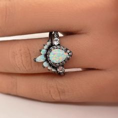 a woman's hand with a white opal and black diamond ring on it