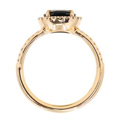 a yellow gold ring with an oval cut black diamond on the center and side stones