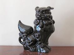 a black foo foo statue sitting on top of a wooden table next to a white wall