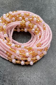 pink and gold beaded stretch bracelets on grey background with space for text or image