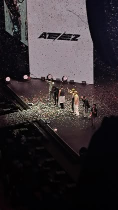 a group of people standing on top of a stage with confetti all over them