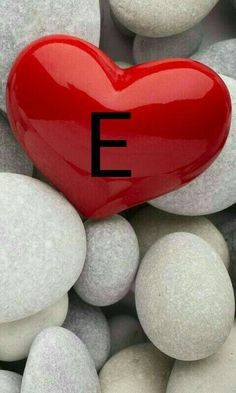 a red heart surrounded by white rocks with the letter e on it