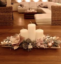 three white candles sitting on top of a wooden table in front of a christmas tree