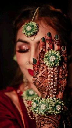 a woman holding her hands up to her face with henna and jewels on it