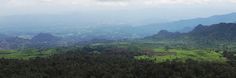 an aerial view of mountains and trees with clouds in the sky over them on a cloudy day