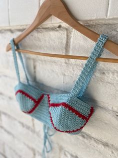 a crocheted bra hanging on a wooden hanger next to a brick wall