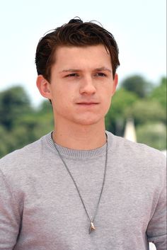 a young man wearing a necklace with a cross pendant on it's neck and looking at the camera