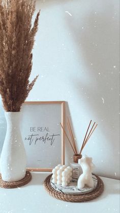 a white vase sitting on top of a table next to a sign and some plants