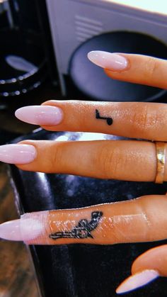 a woman's hand with pink nail polish and music note tattoo on the middle finger