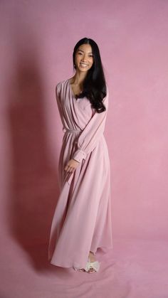 a woman in a long pink dress posing for a photo with her hands on her hips