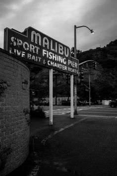 a black and white photo of a sign that says mallu sport fishing pier, live raft & charter boats