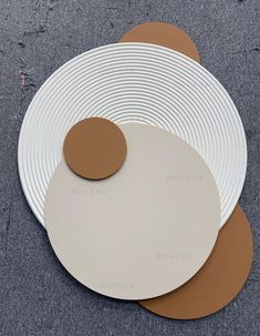 three white plates with brown circles sitting on top of each other in front of a gray floor