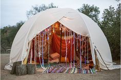 a white tent with red curtains and chains hanging from it's sides on the ground