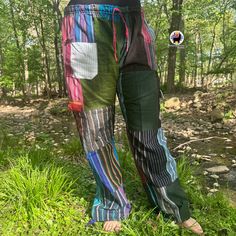 a person standing in the grass with their legs crossed and his pants are multicolored