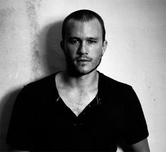 a black and white photo of a man in a t - shirt looking at the camera