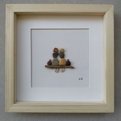 a group of rocks sitting on top of a piece of wood in a white frame