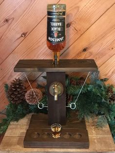 a bottle of beer sitting on top of a wooden table next to pine cones and evergreens