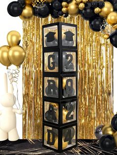 a black and gold graduation party with balloons, streamers and numbers on the wall