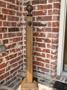 a wooden grandfather clock sitting in front of a red brick wall next to a door