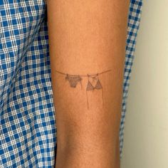 a woman's arm with two clothes hanging on a line tattooed to the side