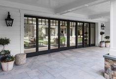 an empty patio with potted plants in front of the glass doors to a house