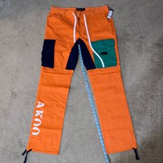 New With Tags Mens A.K.O.O. Sanchez Pants Size 36. They Are In Perfect Condition, Have Not Been Worn, At A Smoke Free, Pet Free Home. Orange Bottoms With Pockets For Outdoor, Casual Orange Bottoms With Side Pockets, Casual Orange Straight Leg Pants, Orange Cotton Bottoms With Pockets, Orange Cotton Cargo Bottoms, Cotton Cargo Bottoms In Orange, Casual Orange Bottoms With Cargo Pockets, Orange Straight Leg Bottoms With Pockets, Casual Orange Cargo Pants For Streetwear