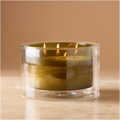 three lit candles in a glass container on a table