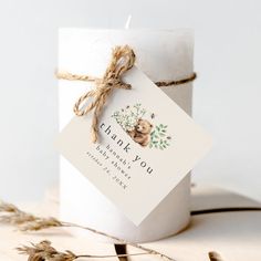 a white candle with a thank you tag on it