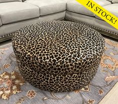 a leopard print ottoman sitting on top of a rug in front of a gray couch