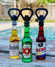 three different types of liquor bottles sitting next to each other on a wooden table near a swimming pool