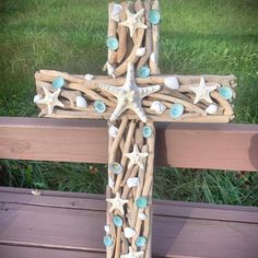 a cross made out of driftwood with seashells and starfish on it