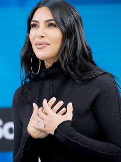 a woman with her hands folded in front of her chest and looking off to the side