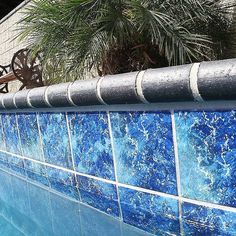 a blue tiled wall next to a swimming pool