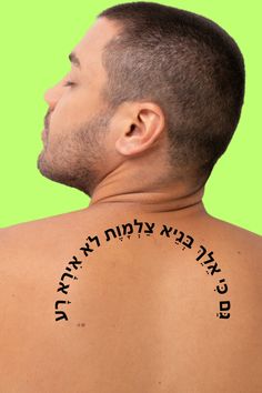 the back of a man's neck with hebrew writing on his upper half and lower half