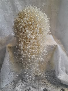 a vase filled with lots of white flowers on top of a lace covered table cloth