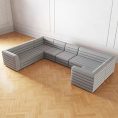 a large gray couch sitting on top of a hard wood floor next to a wall