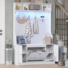 a white coat rack with shoes and umbrellas on it next to a stair case